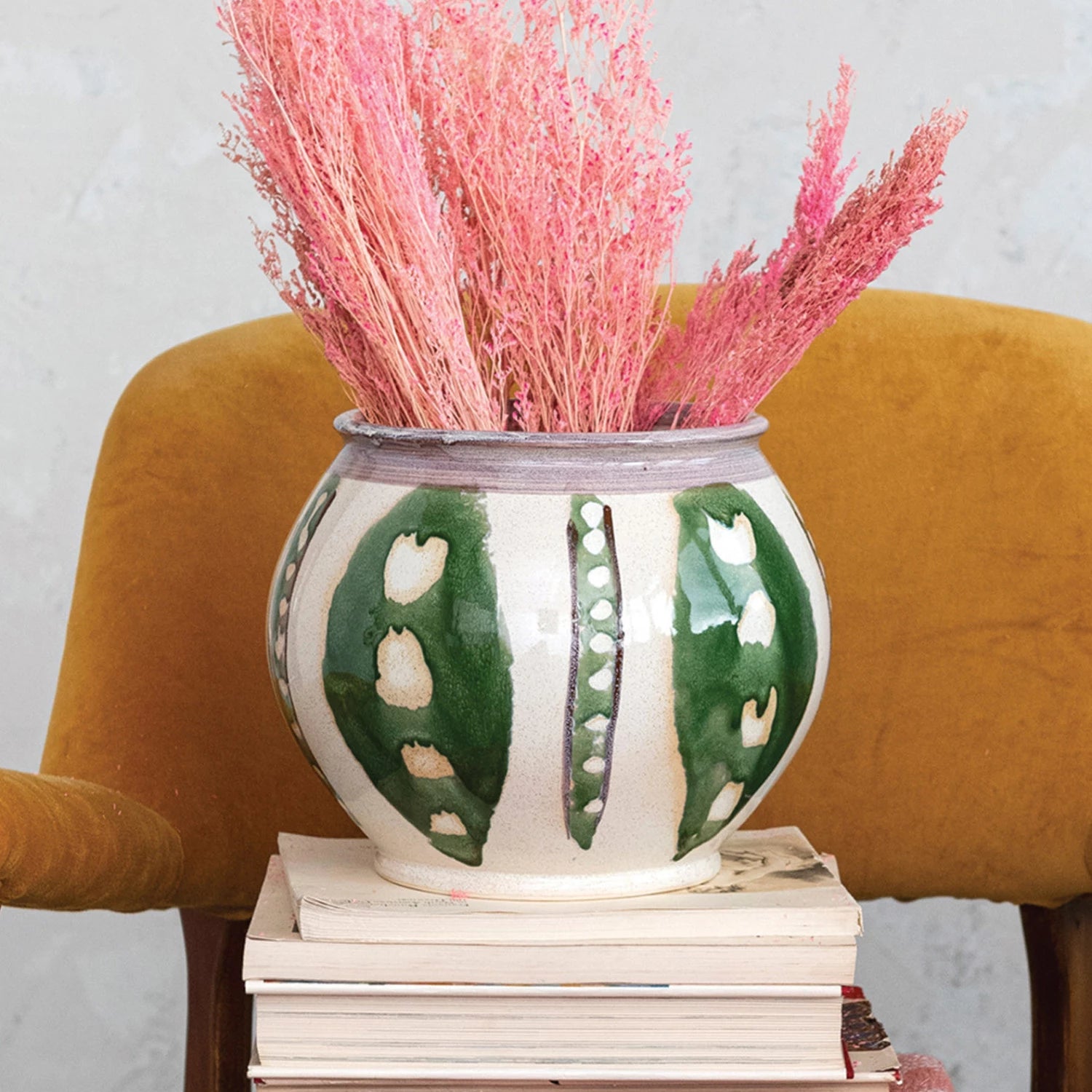 Stoneware Planter with Green Design set on a stack of books and filled with dried pink stems