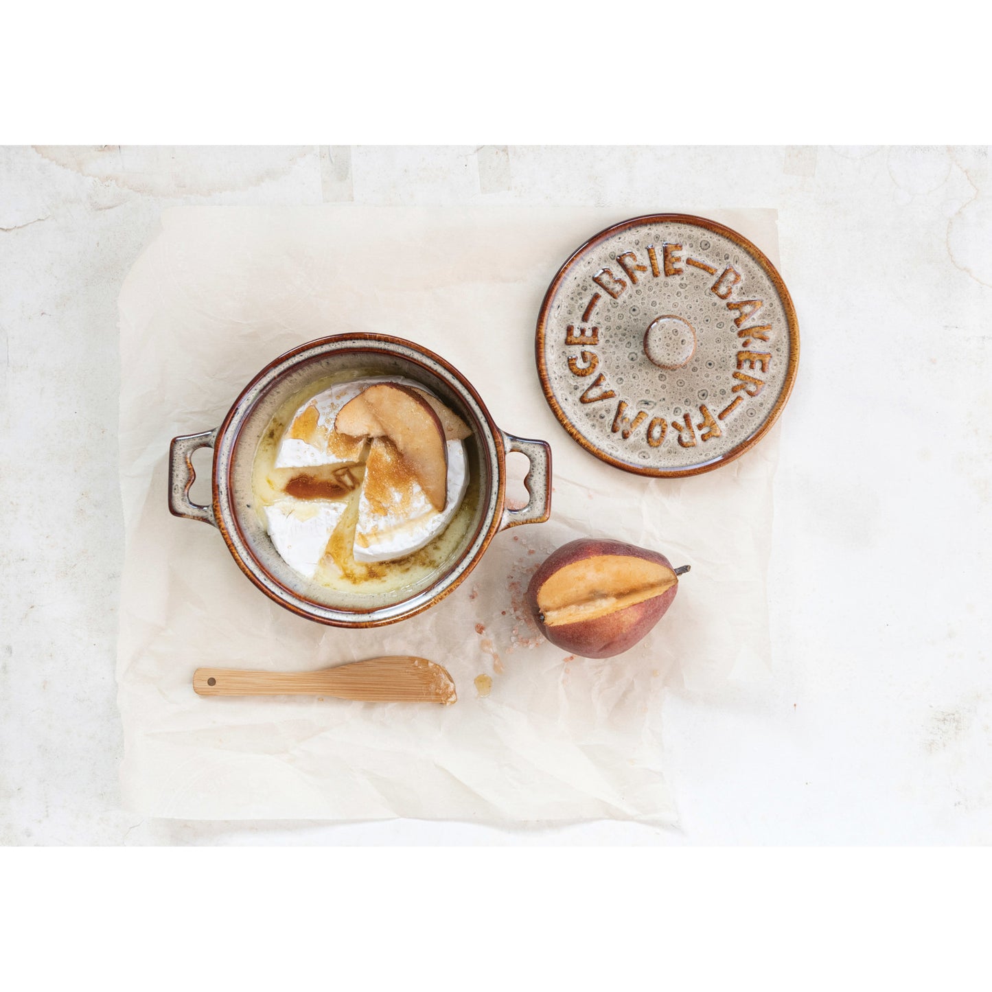 small Ceramic baking dish with a brie and pears in it on a marble surface