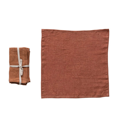 set of folded rust Stonewashed Linen Napkins tied with ribbon and one displayed laying flat on a white background
