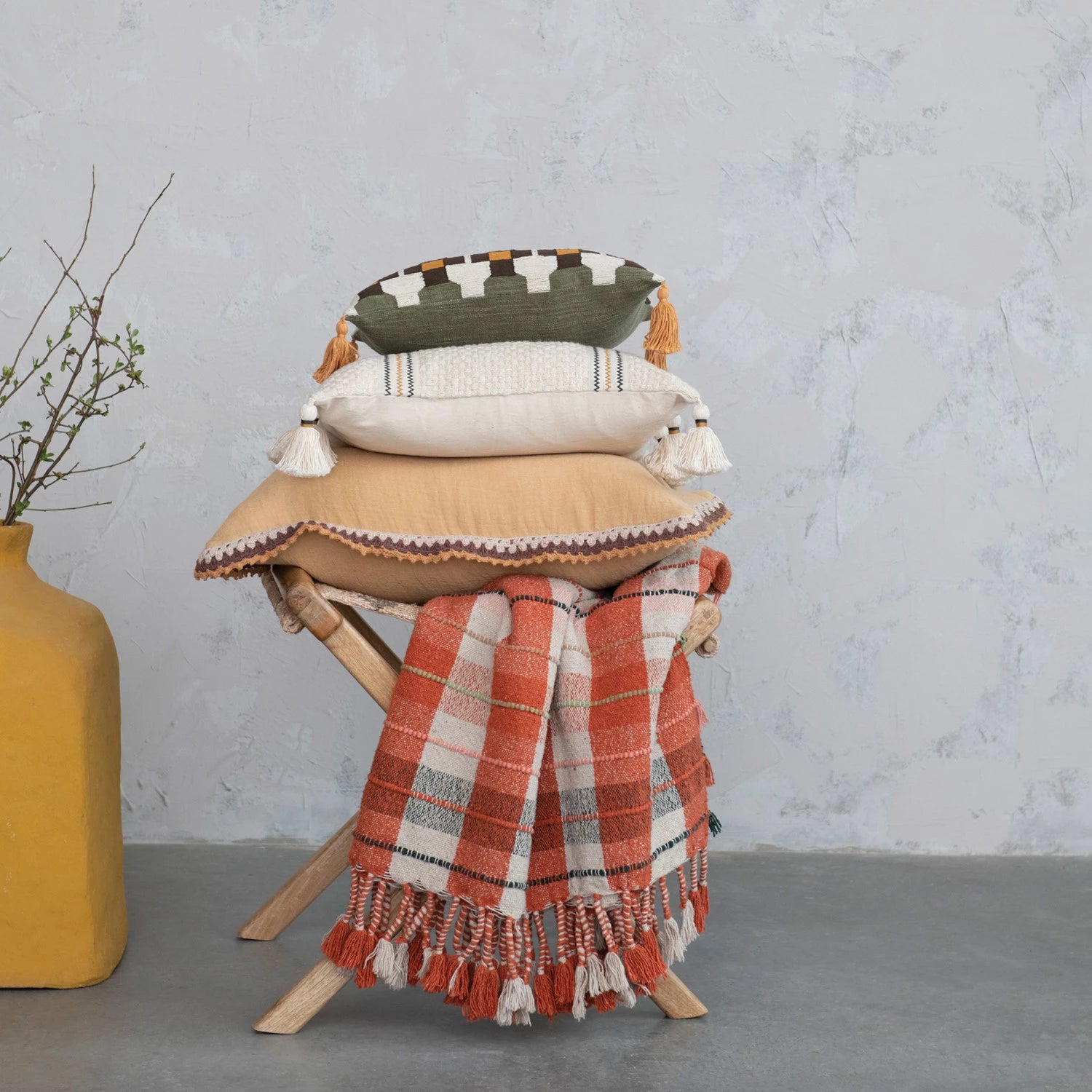 plaid Throw displayed on a wooden folding chair beneath three decorative pillows and next to a square yellow vase