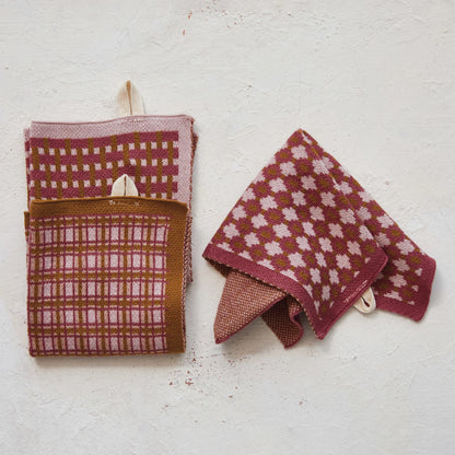 3 styles of pink and brown knitted cloths arranged on a plaster background.