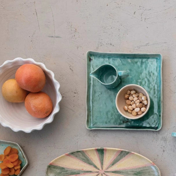 aqua tray and a collection of ceramic dishes filled with fruits and nuts on a plaster background 