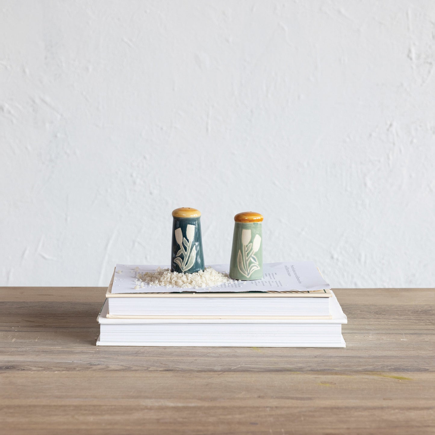 salt and pepper shakers set on a stack of books with a small pile of salt.