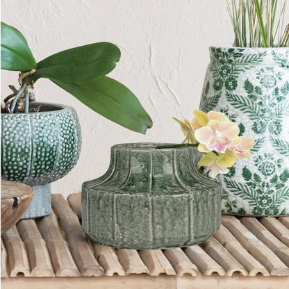 Terracotta Vase with Embossed Lines set on a table with other vases and greenery.