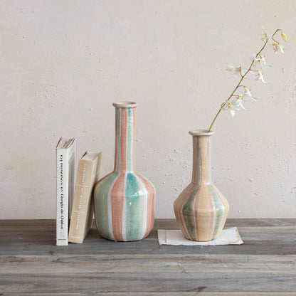 2 style and sizes of terracotta vases arranged on a table with books.