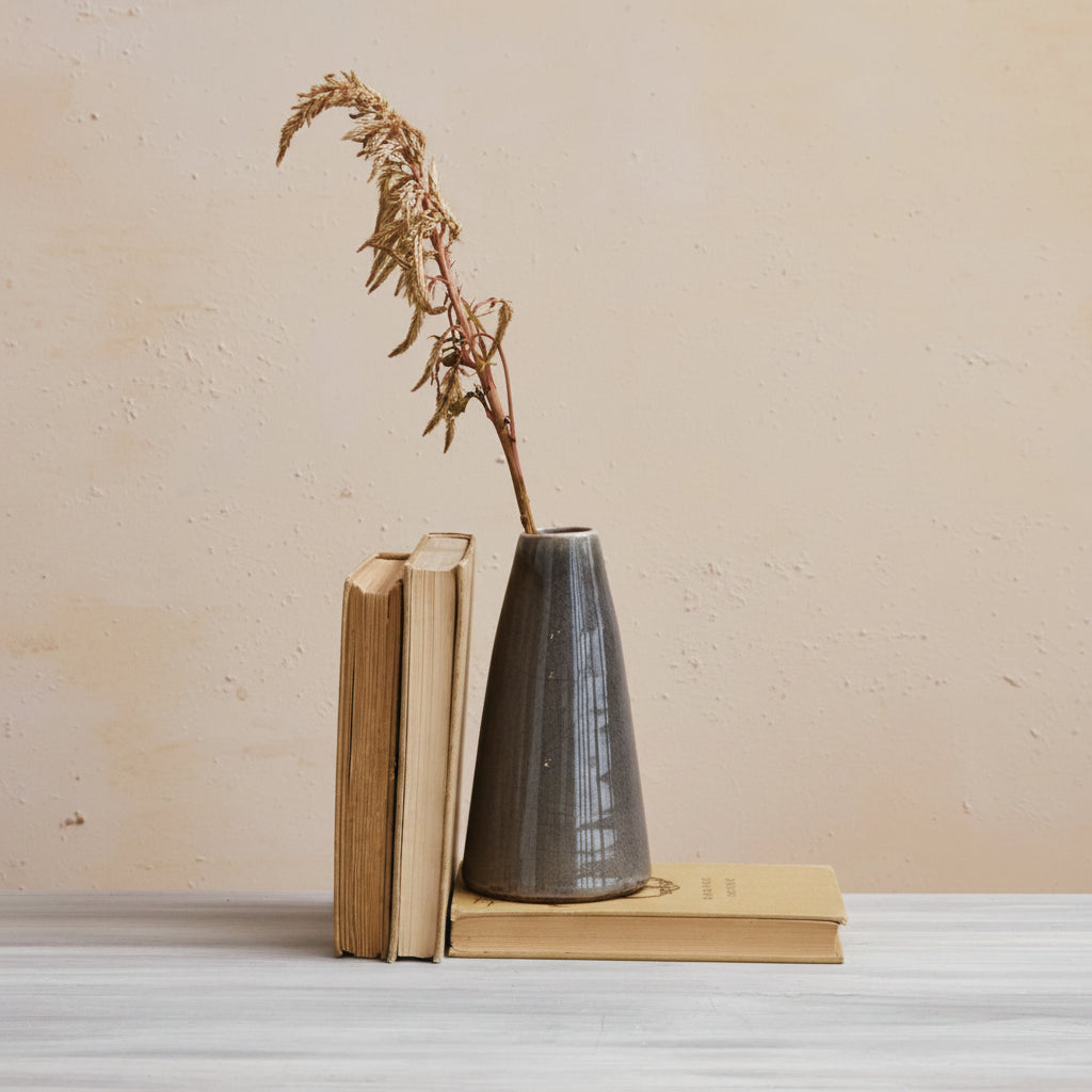 larger grey bud vase set with books in front of a plaster background