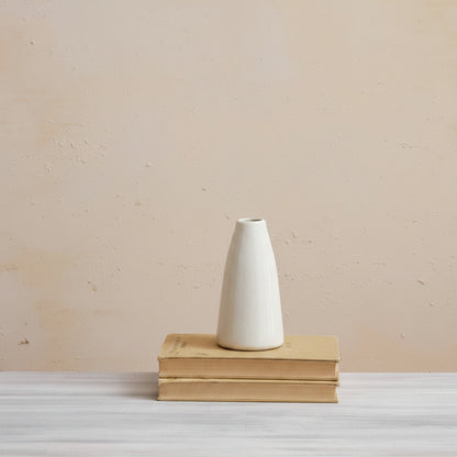 medium cream vase set on a stack of books with a palster background
