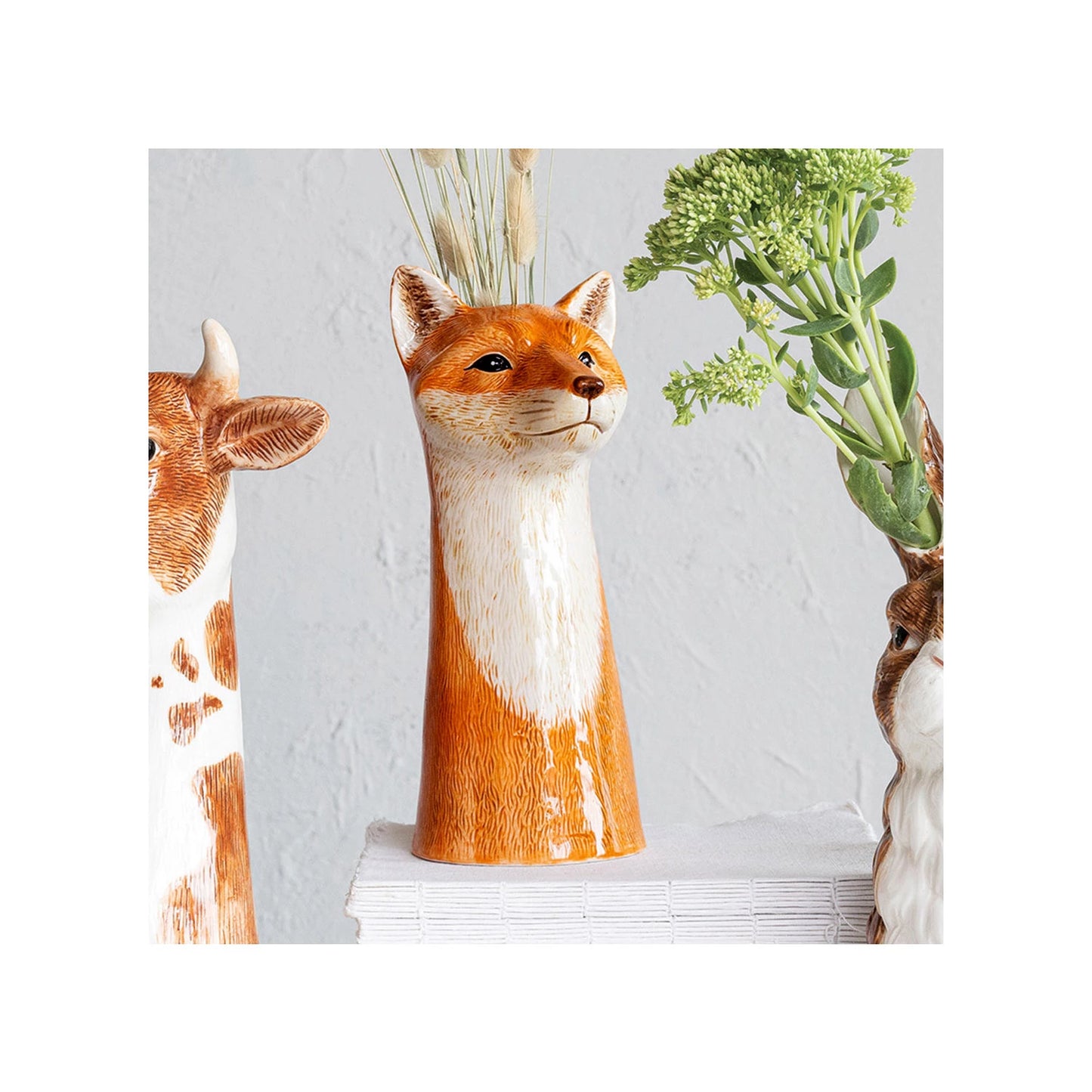 Fox-shaped vase with plants on a light gray background