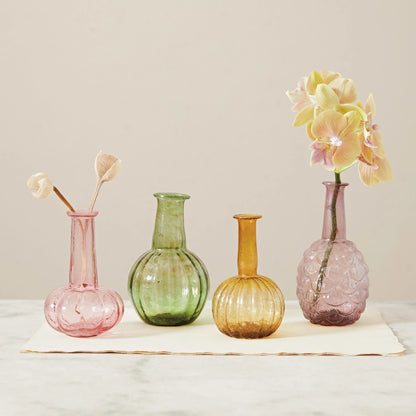 3 colors and designs of recycled glass vases on  table, 2 of them have floral in them.