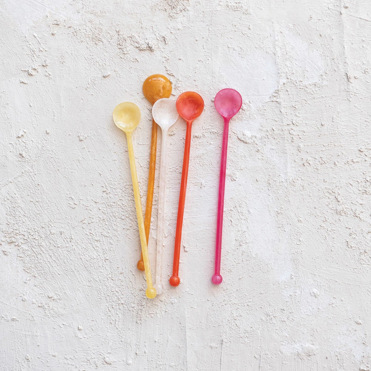 colorful spoons on a textured white surface