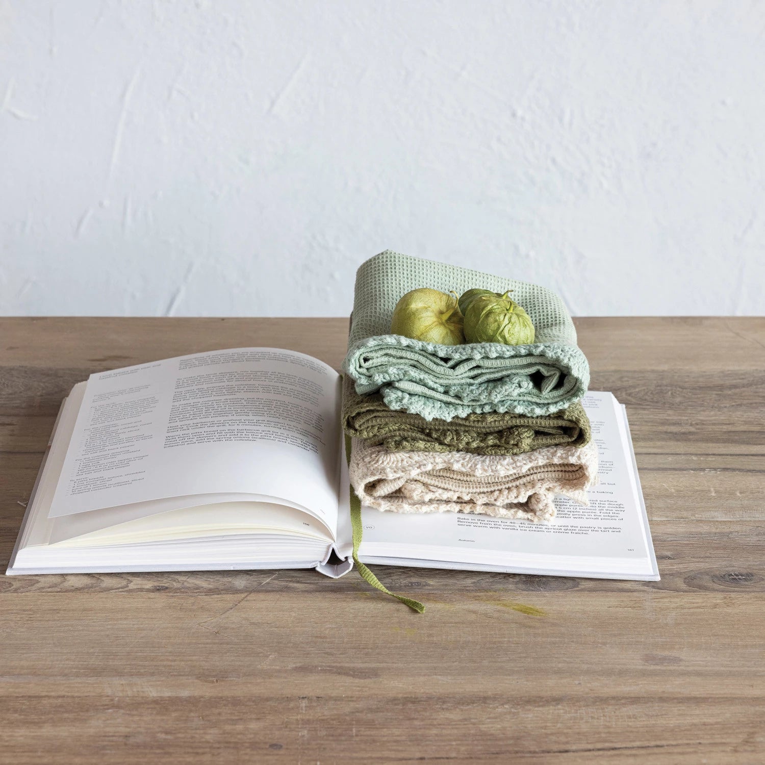 stack of folded towels set on an open book on a wooden table.