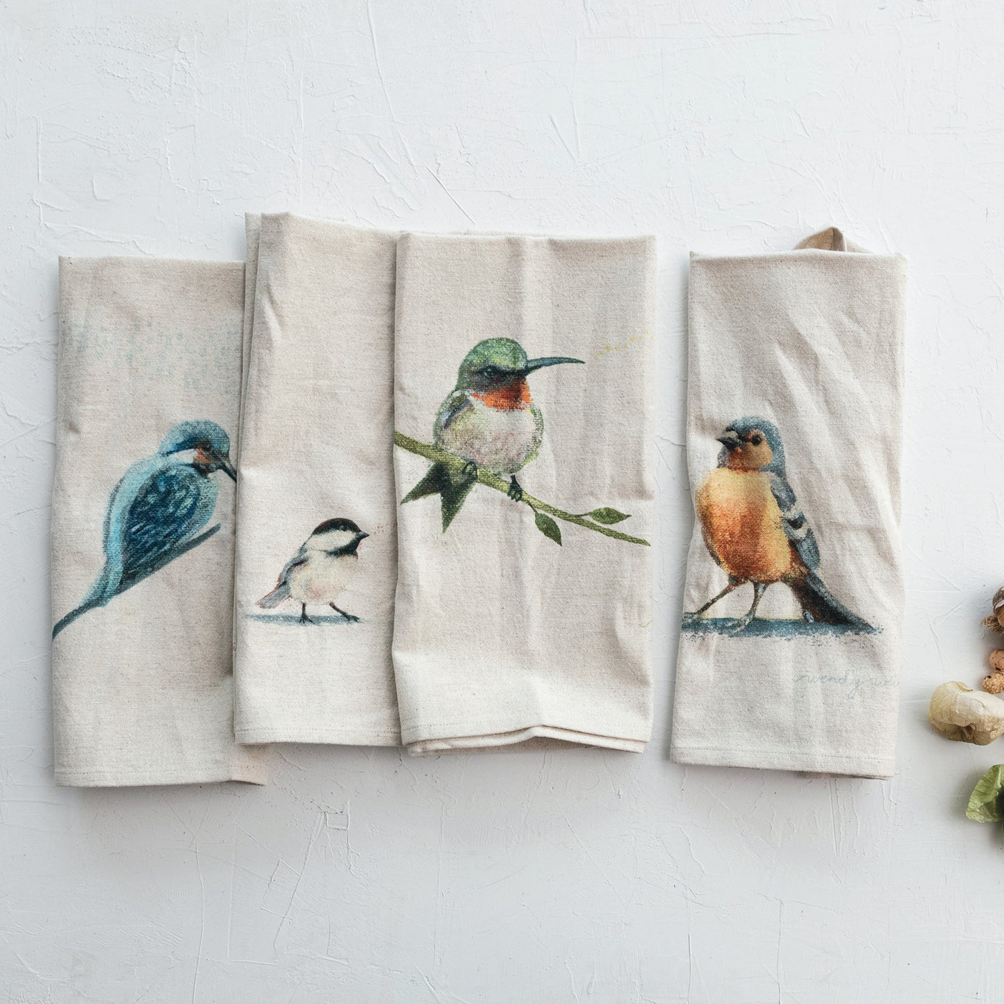 4 bird towels folded on a plaster background