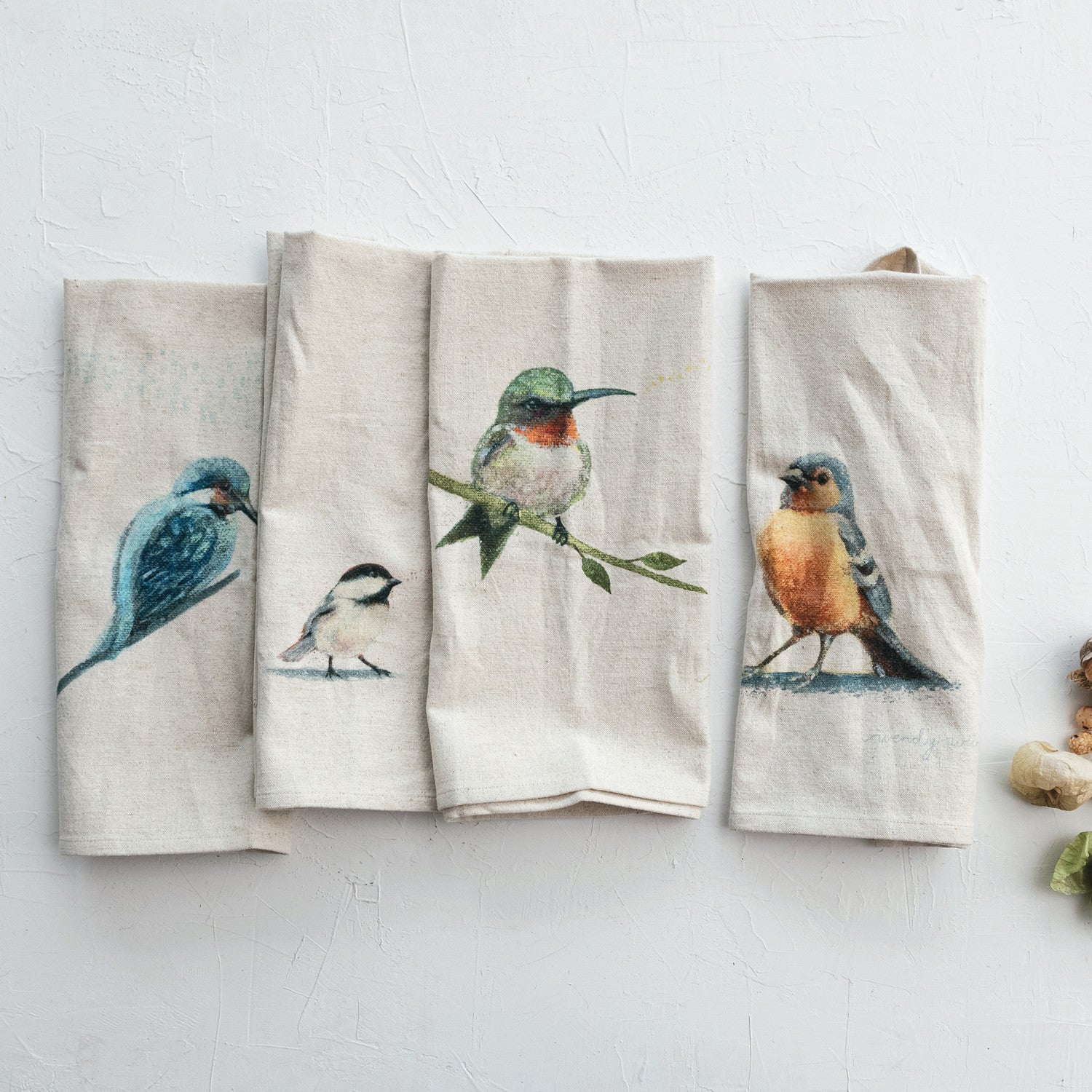 4 bird towels folded on a plaster background
