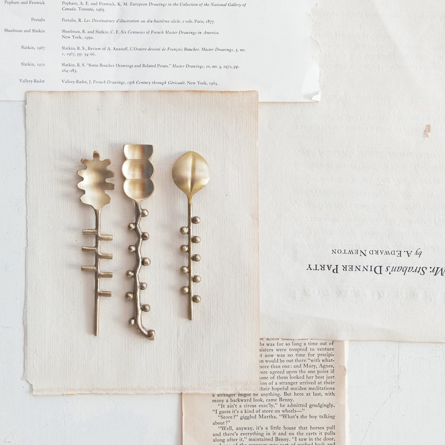 3 styles of brass spoons arranged on a piece of paper.