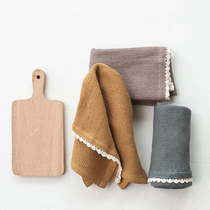 wood board and 3 different colored tea towels folded up