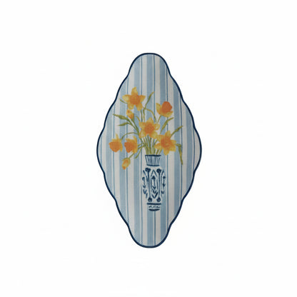 blue and white stripe platter painted with a design of daffodils in a vase on it