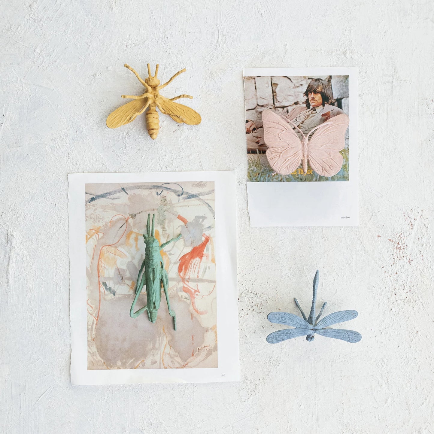 Decorative insects and artwork on a textured white surface.
