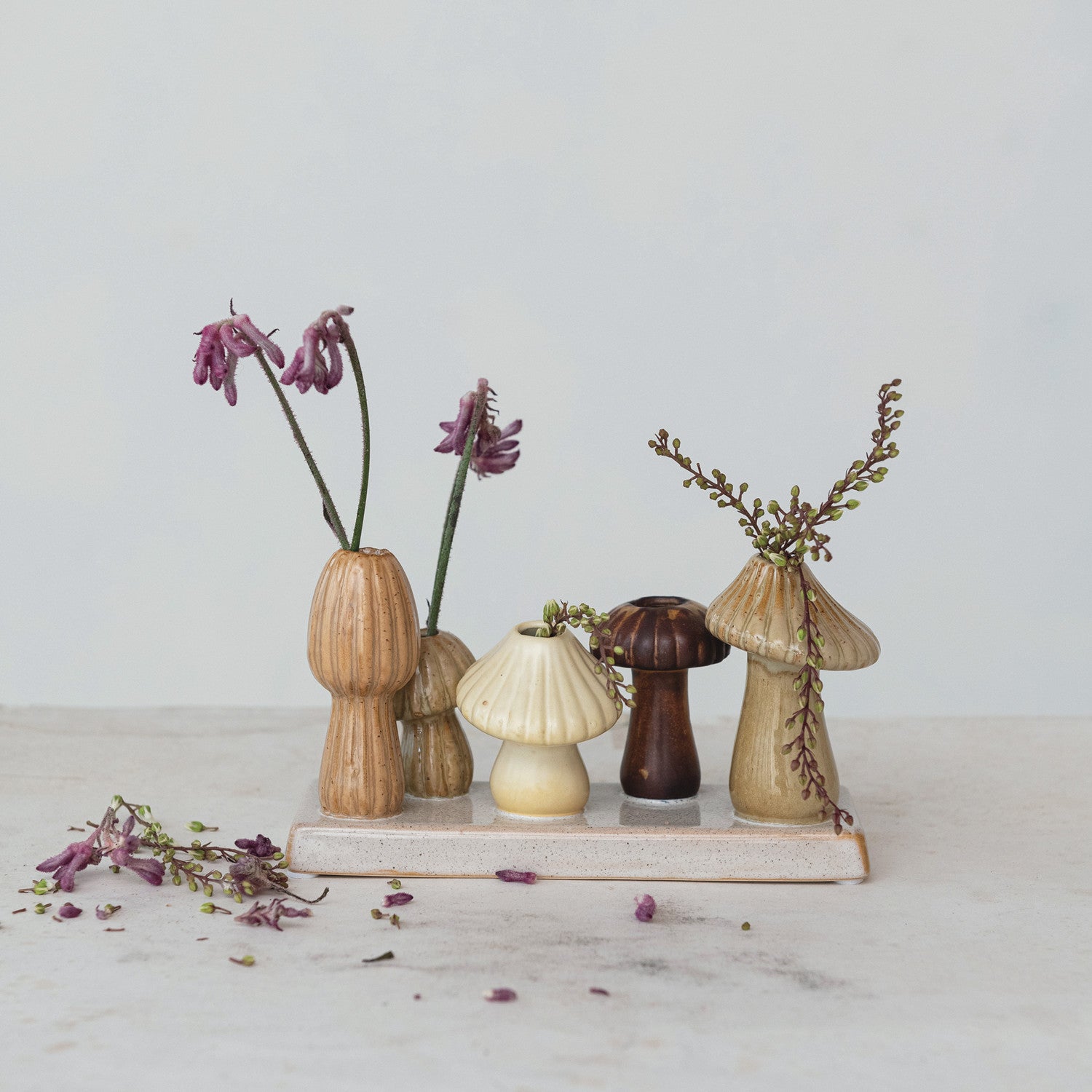 stoneware mushroom vases on a stoneware tray with dried greenery in them.