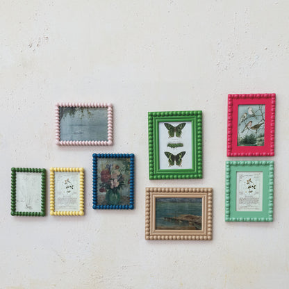 textured wall with an array of colorful framed printed hung on it