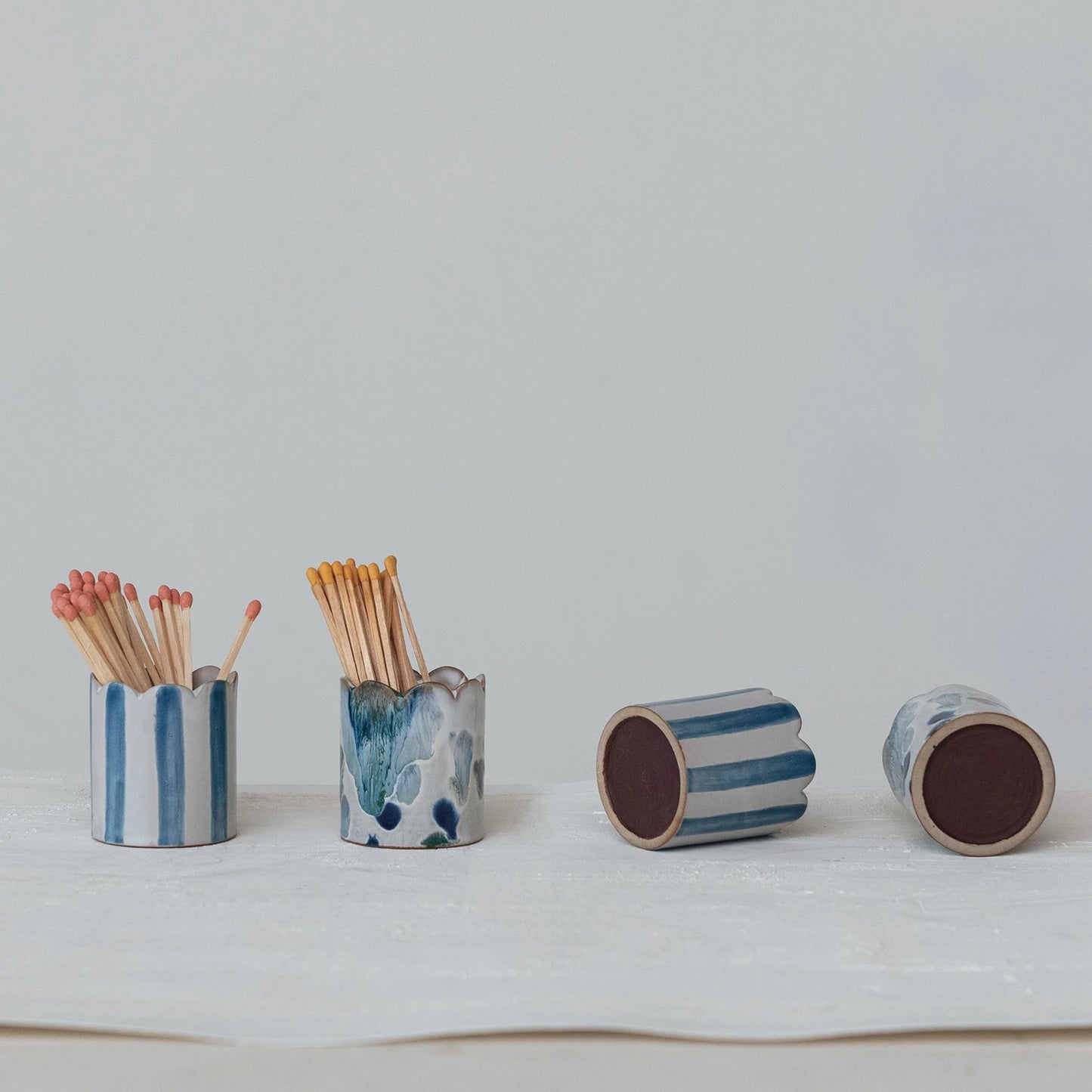 assorted ceramic blue and white match holders with matches on a light gray background