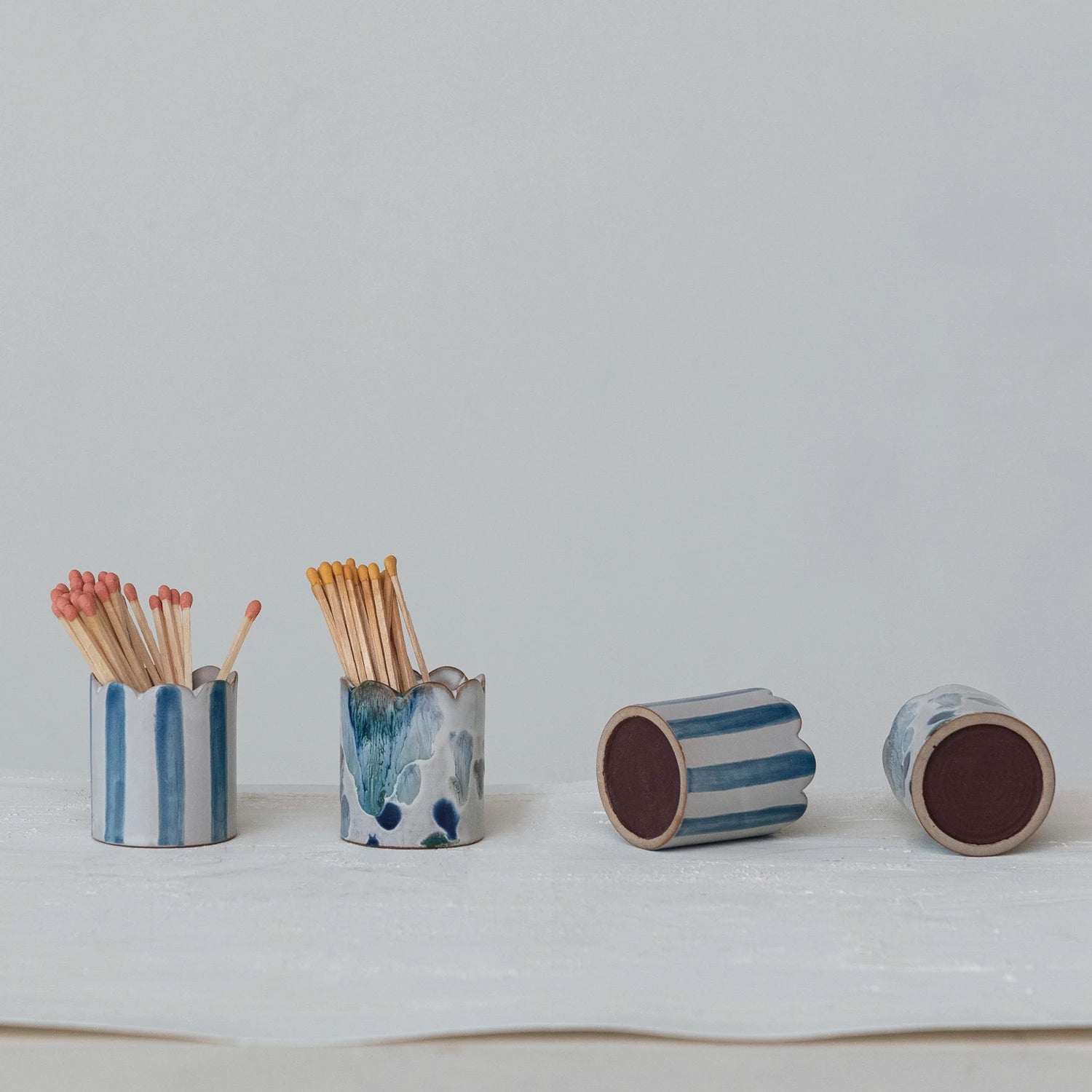 assorted ceramic blue and white match holders with matches on a light gray background