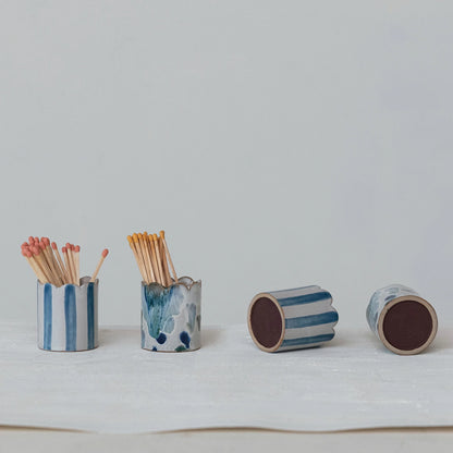 assorted ceramic blue and white match holders with matches on a light gray background