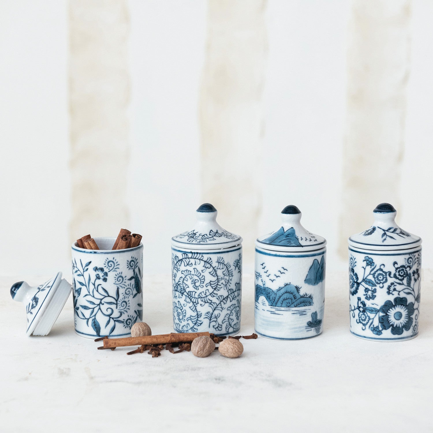 4 blue and white patterned jars arranged on a counter with spices.