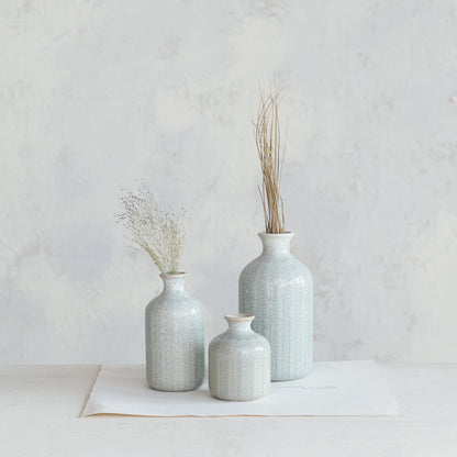 3 sizes of stoneware vase arranged on a table, medium and large vase have dried greenery in them.