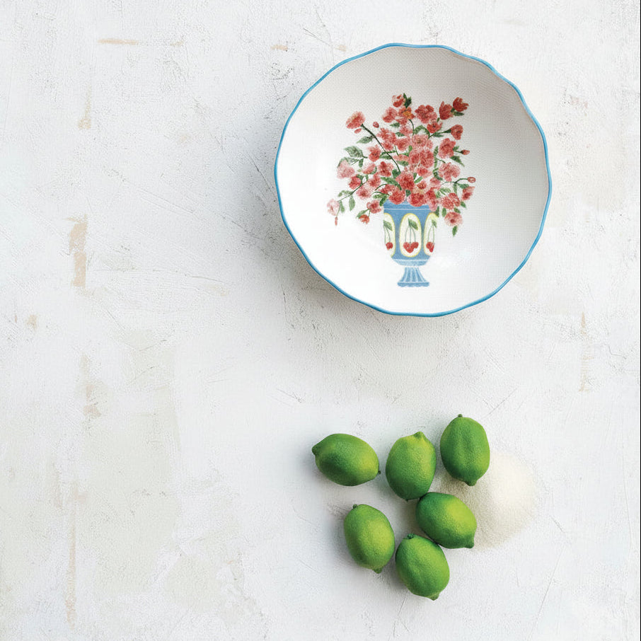 Decorative bowl with floral design on a white plaster surface with limes.