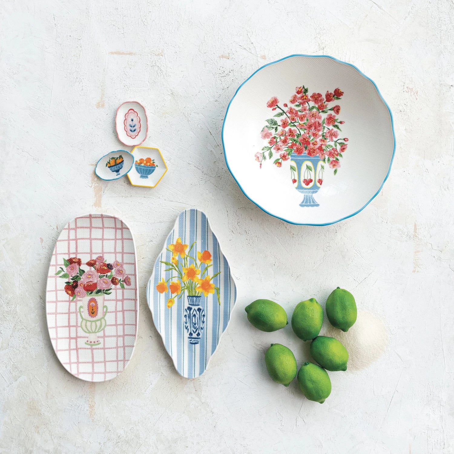 assorted Decorative plates and a bowl in various sizes with floral designs on a white surface with limes.