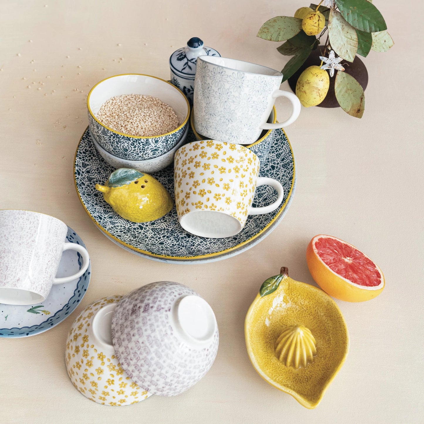 Assorted ceramic tableware with lemons and a grapefruit on a light background