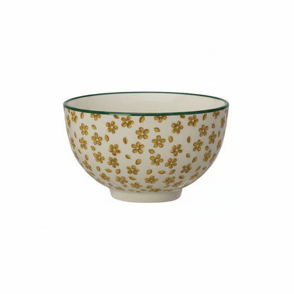 Ceramic bowl with mustard yellow floral pattern and green rim on a white background