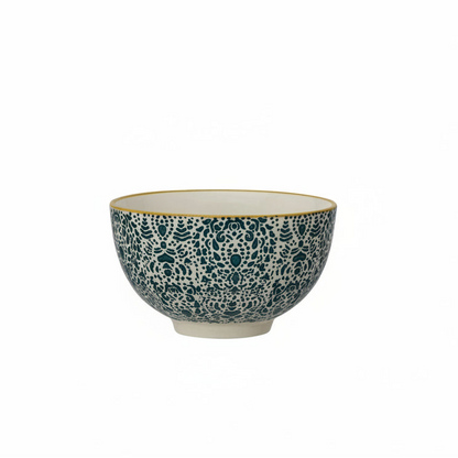 Decorative ceramic bowl with blue pattern and mustard colored rim on a white background
