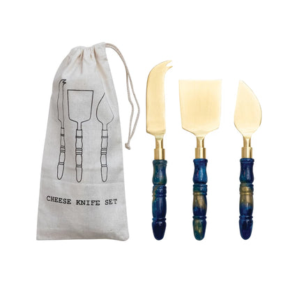 Set of three cheese knives with blue handles and a matching drawstring bag on a white background