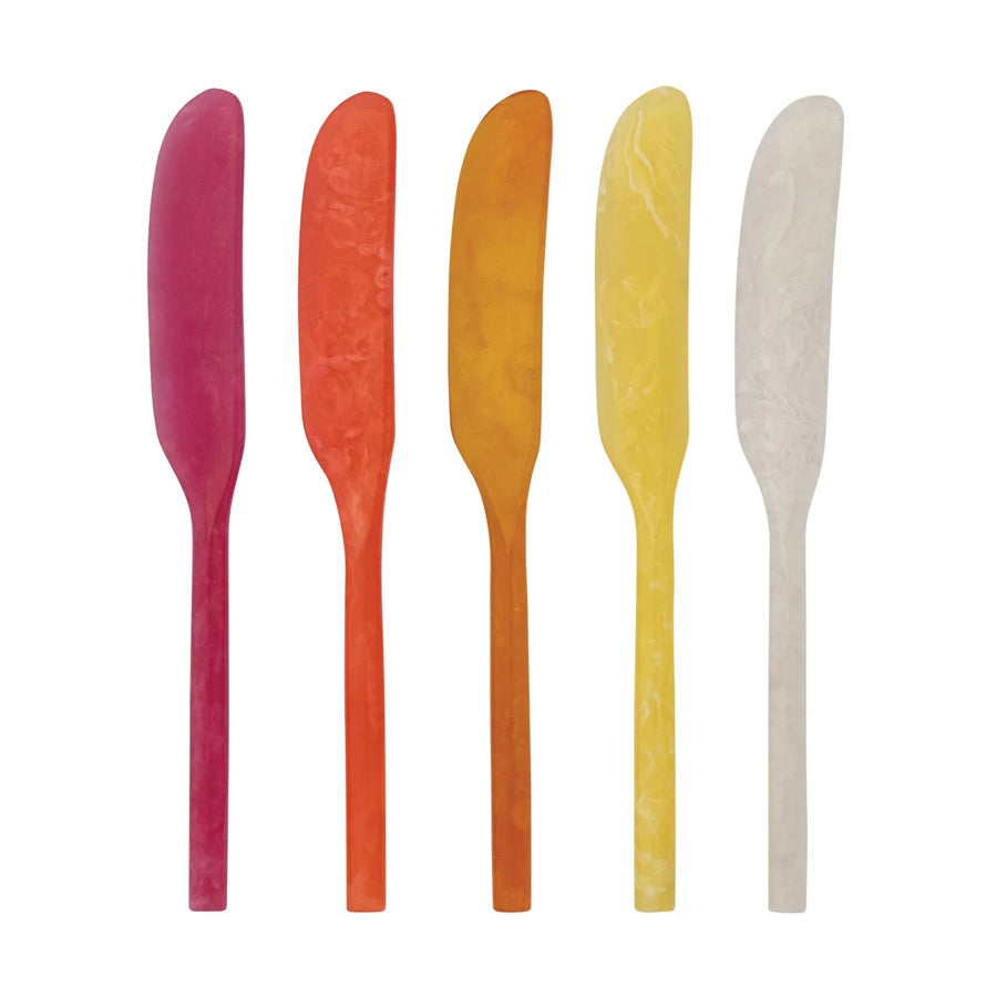 Five colorful butter knives on a white background