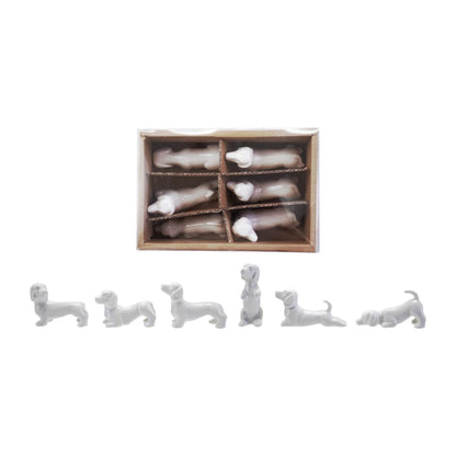 Set of white ceramic dog figurines and  a box containing similar figurines on a white background.