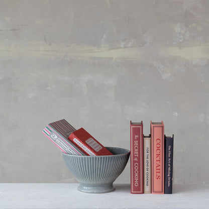Stack of cookbooks in a gray bowl against a gray background