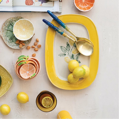 Table setting with platter, bowls, lemons, oranges, and a book on a light background