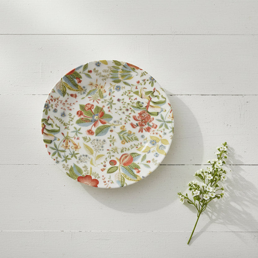 salad plate with small floral design shown on a white wooden background with a sprig of greenery