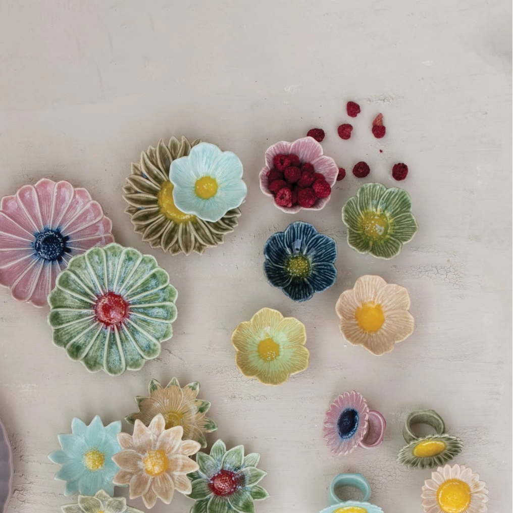Colorful ceramic flower-shaped bowls on a light wooden surface