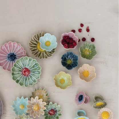 Colorful ceramic flower-shaped bowls on a light wooden surface