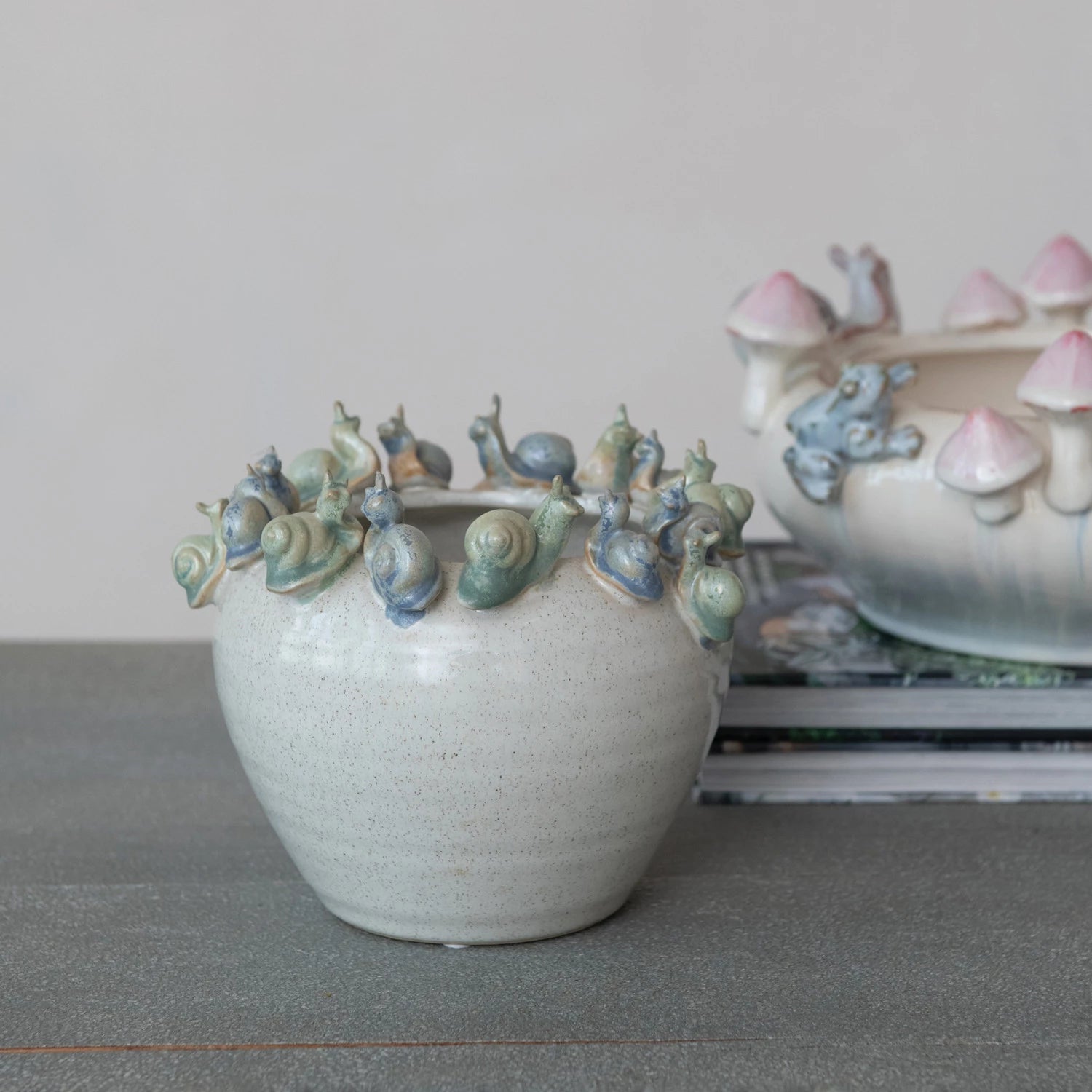 Ceramic vase with snail decorations on a gray surface