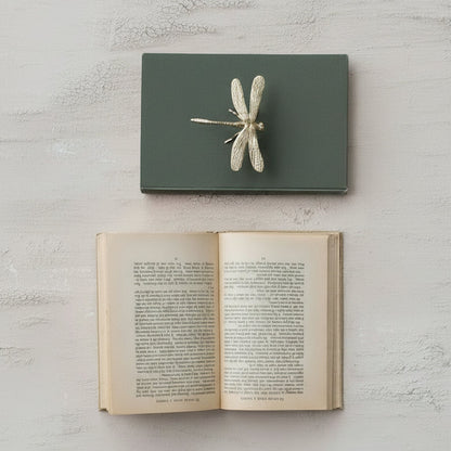 dragonfly sitter on a closed book above an open book