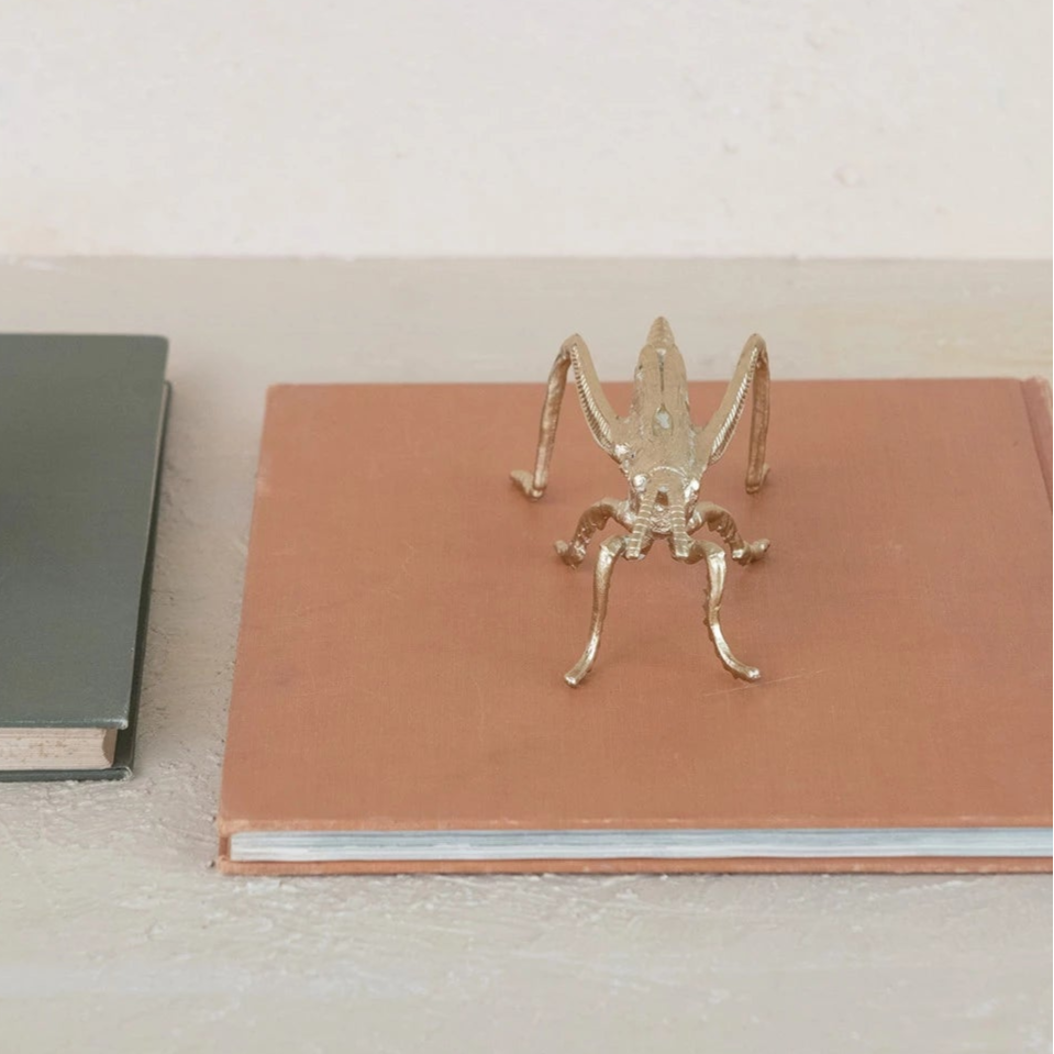 gold grasshopper set on a book