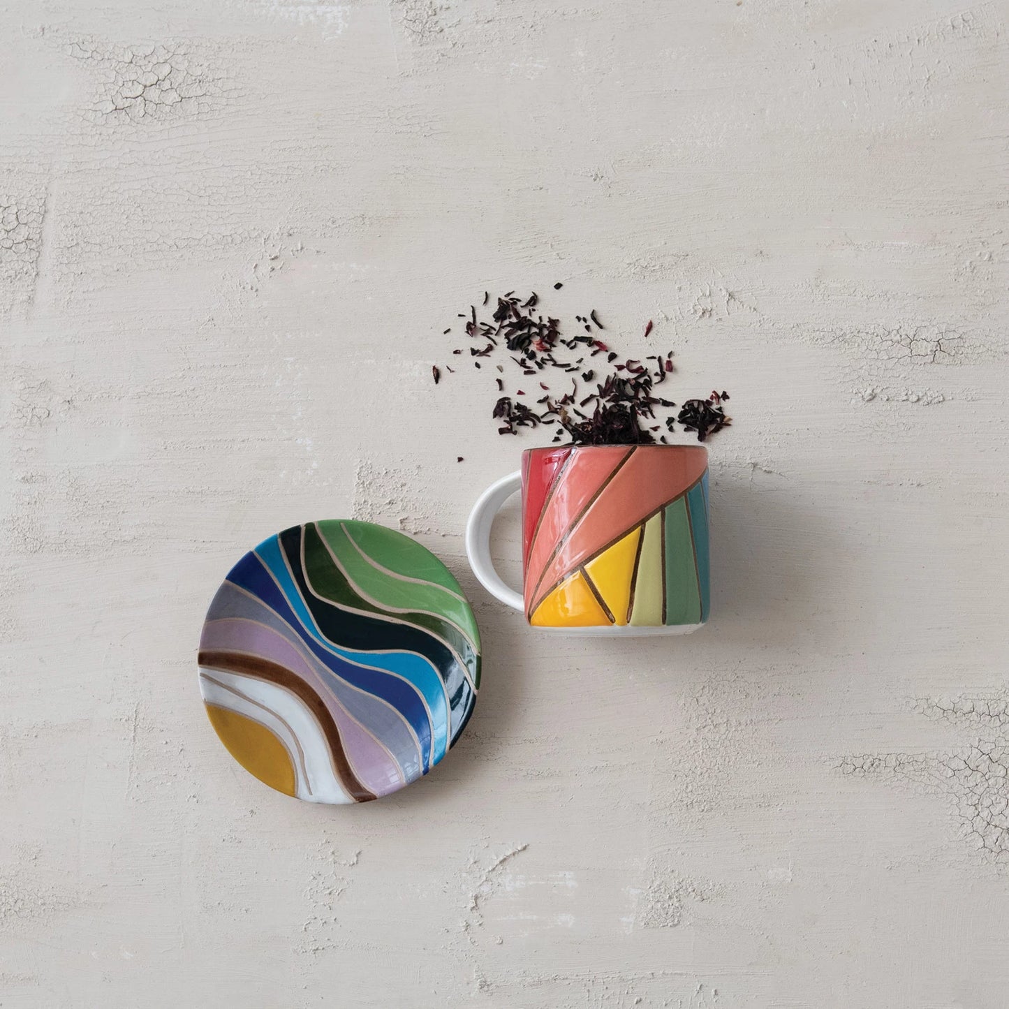 Colorful plate and mug set on a plaster surface