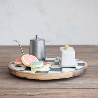 black and white check lazy susan with a tea pot, butter dish, and cookies on it set on a wooden table
