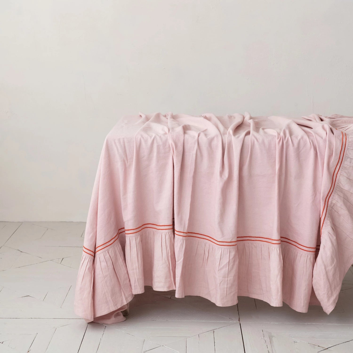 Pink tablecloth with red trim draped on a table