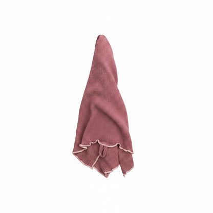 textured mauve tea towel with light pink stitching on hem draped on a white background
