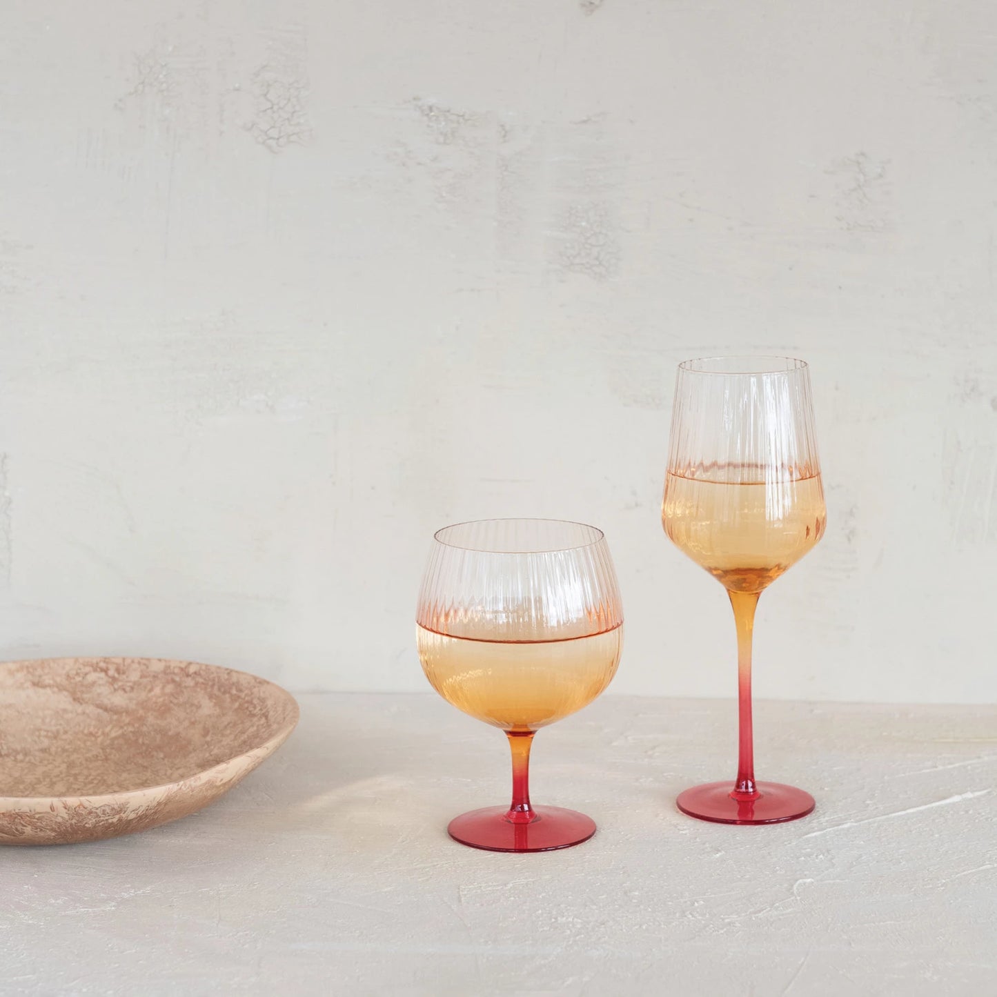 Two wine glasses with gradient design and filled with beverage on a light surface.