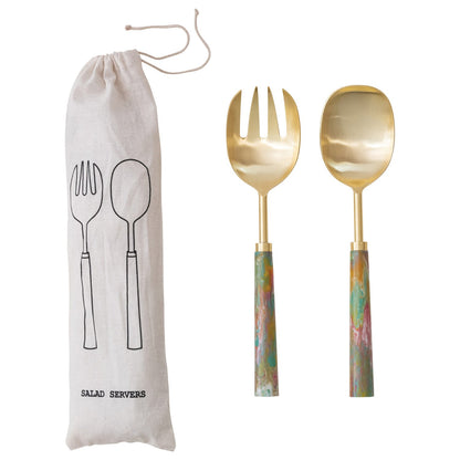 Gold salad servers with colorful resin handles next to a drawstring bag with utensil illustrations on a white background